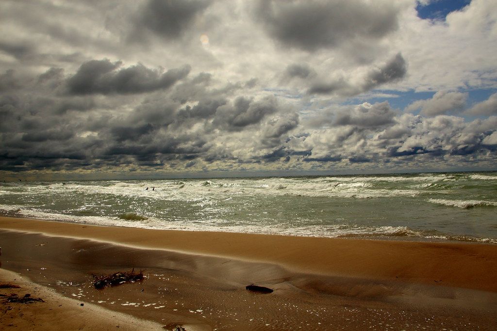 Clouds and light reflecting on Lake Michigan with gull on the beach