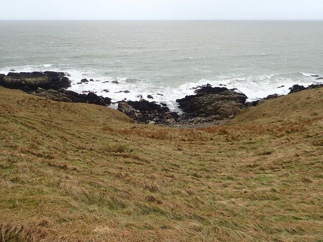 Grassy hillside dropping down to rocks and shingle