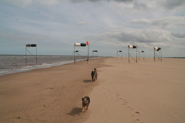 Markers and joggers on the beach at low tide on the Donna Nook bombing range